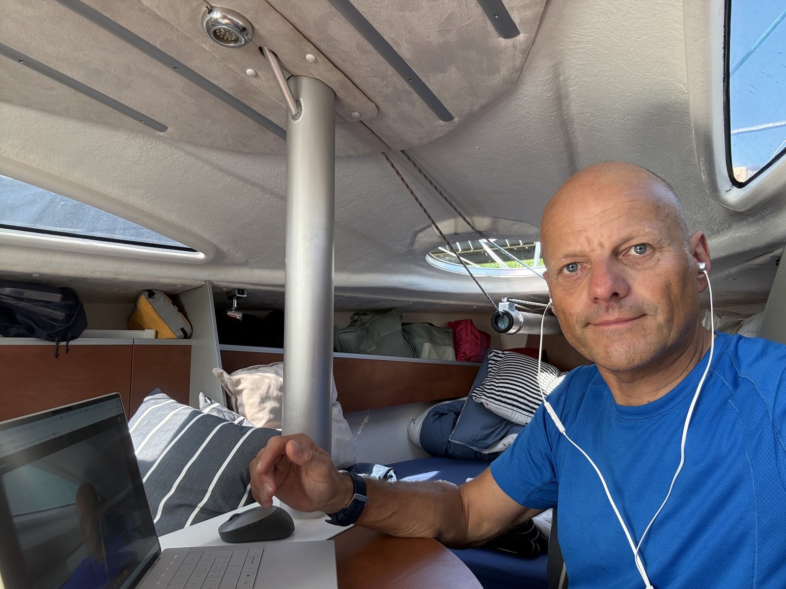 Volkmar Ritter arbeitet mit Laptop in der Kajüte eines Segelboots